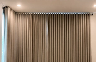 Modern floor-length pleated curtains in a minimalist bedroom interior with soft neutral tones.
