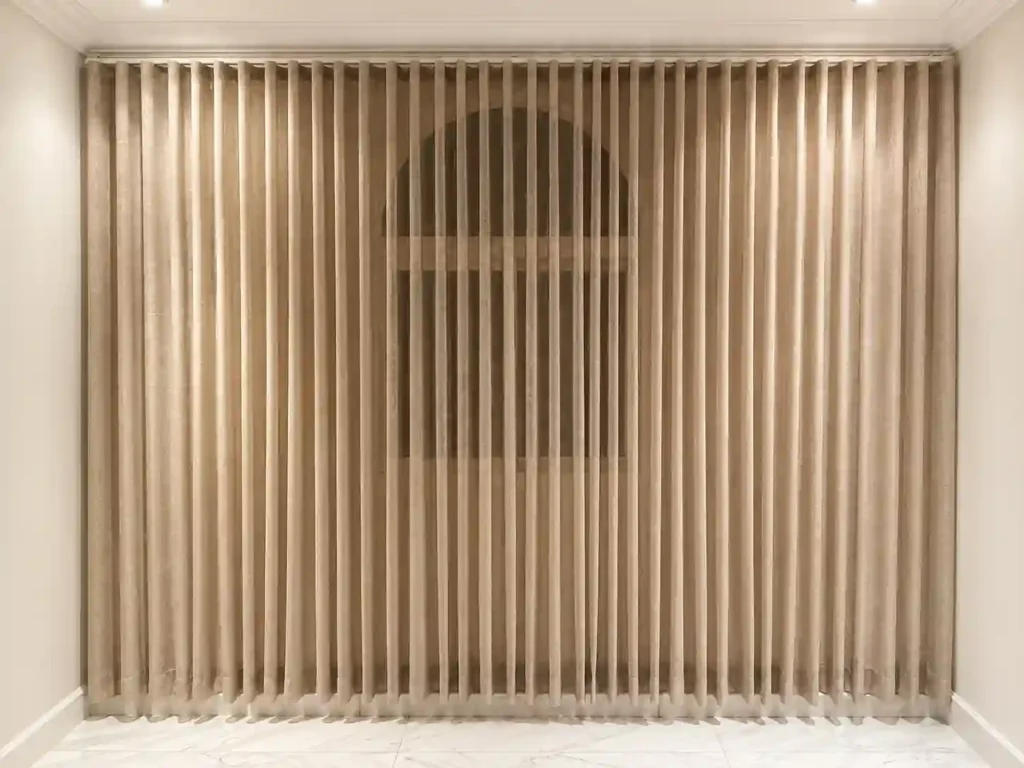 Beige pleated curtains on a decorative window frame.