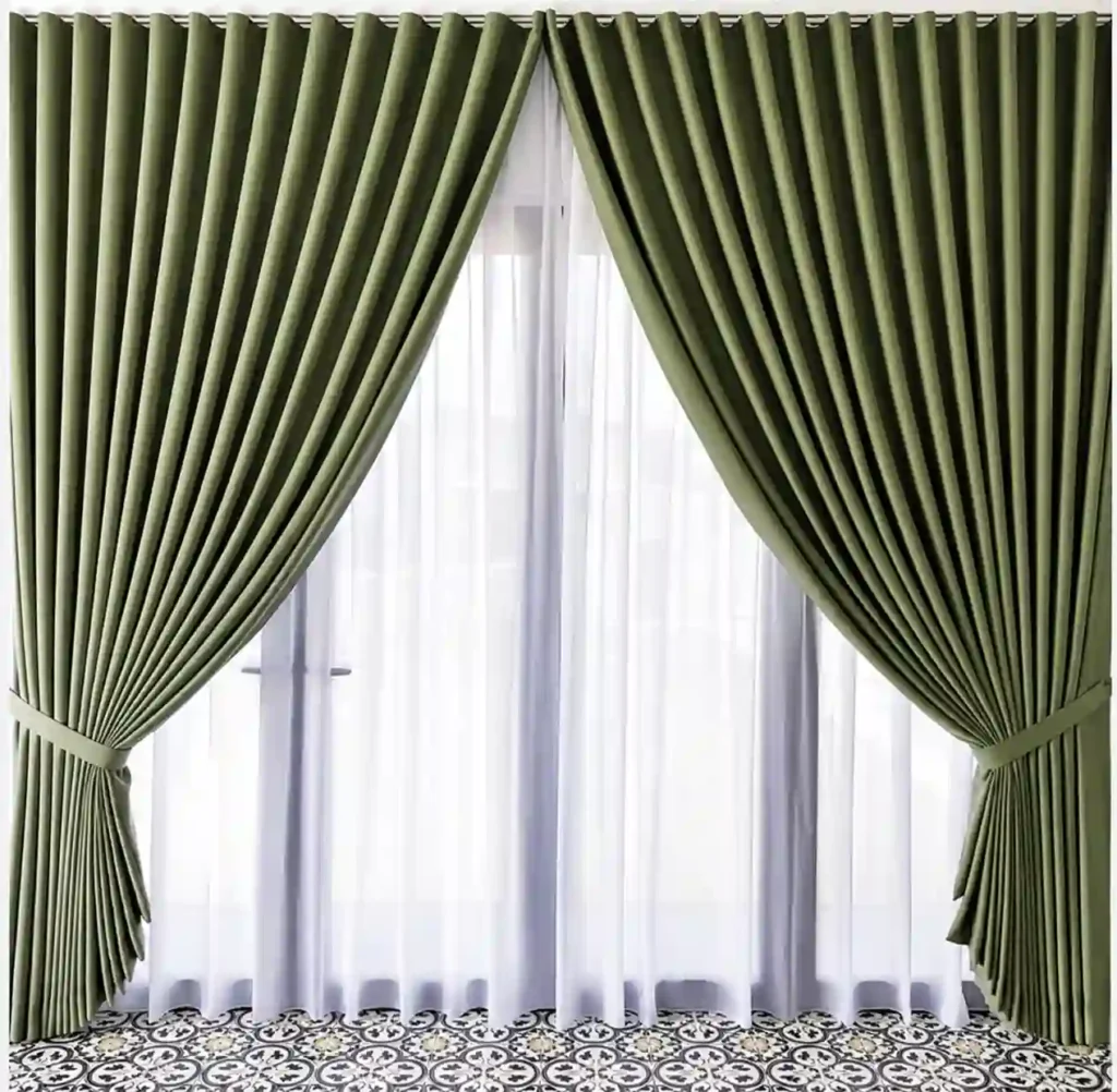 Green blackout curtains with white sheer curtains installed in a modern living room by trusted curtain companies in Saudi Arabia.