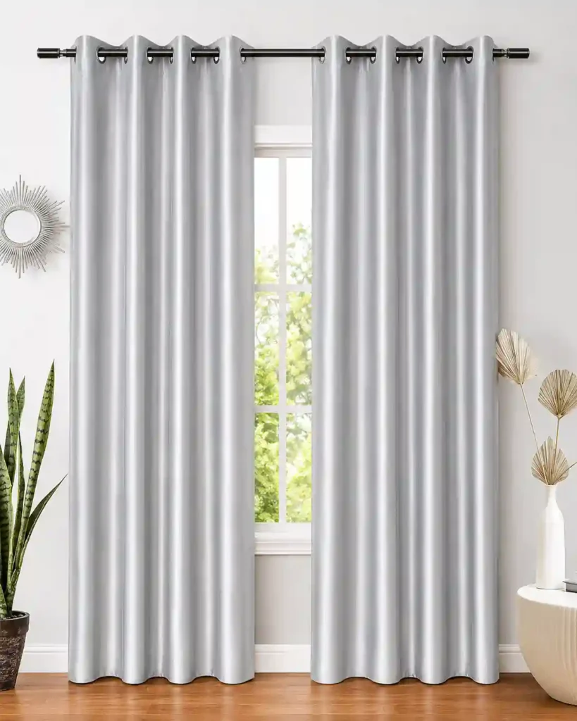 Silver eyelet curtains hanging on a modern window.